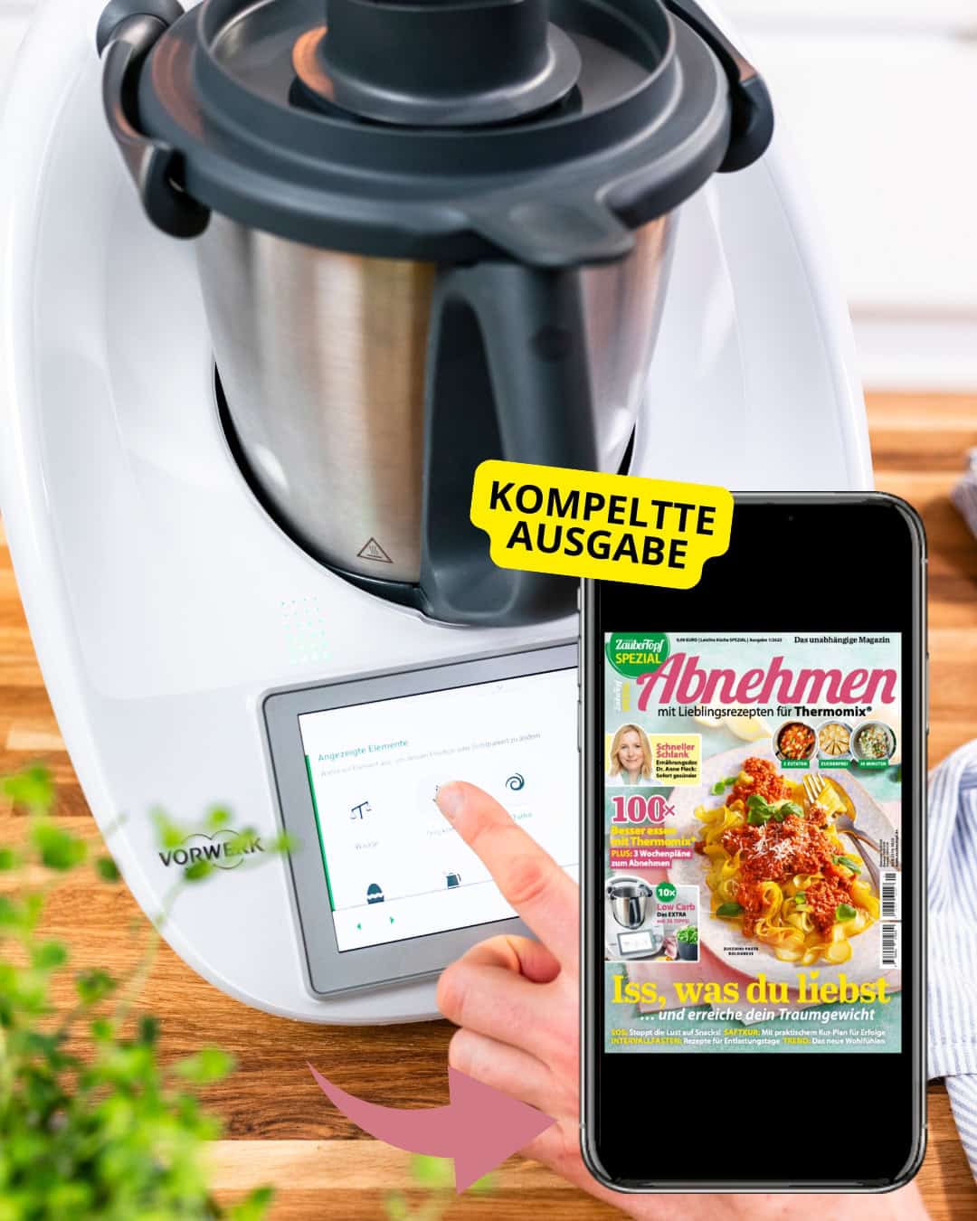 Ein Thermomix und daneben ein Smartphone mit geöffnetem E-Book mit der Thermomix Fit Spezial Ausgabe